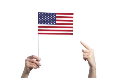 Güzel bir kadın eli, beyaz arka planda izole edilmiş diğer elinin parmağını gösterdiği bir Birleşik Devletler bayrağını tutuyor..