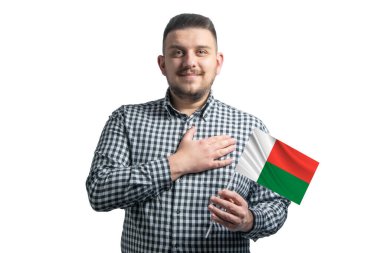 Madagaskar 'ın bayrağını tutan beyaz bir adam elini kalbinin üzerinde tutuyor. Madagaskar' a sevgilerle izole edilmiş beyaz bir zemin üzerinde..