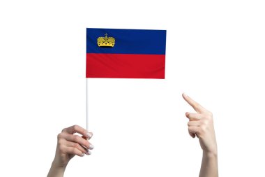 Güzel bir kadın eli, beyaz arka planda izole edilmiş diğer elinin parmağını gösterdiği bir Lihtenştayn bayrağını tutuyor..