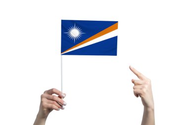 Güzel bir kadın el, beyaz arka planda izole edilmiş diğer elinin parmağını gösterdiği bir Marshall Adaları bayrağını tutuyor..