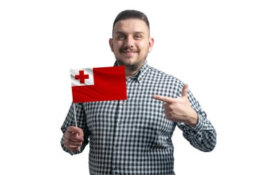 Beyaz adam Tonga 'nın bayrağını tutuyor ve diğer elini beyaz arka planda izole edilmiş bayrağa doğrultuyor..
