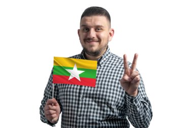 Beyaz adam elinde Myanmar 'ın bayrağını tutuyor ve beyaz arka planda izole edilmiş iki parmak gösteriyor..