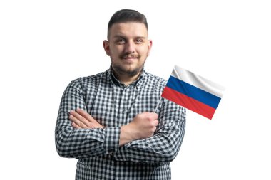 Beyaz adam elinde Rusya bayrağı, beyaz bir arka planda kollarını kavuşturarak gülümsüyor..