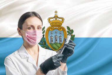 Kız doktor, San Marino bayrağının arka planına karşı aşı hazırlıyor. Aşı konsepti San Marino.