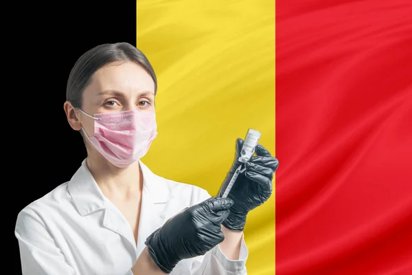 ベルギー国旗を背景に少女医師が予防接種の準備をしています 予防接種のコンセプト ベルギー — ストック写真