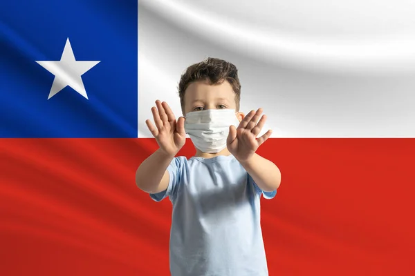 戴着保护面具的白人小男孩 背景是智利国旗 用手做一个停车标志 呆在家里 图库图片