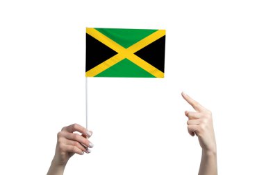 Güzel bir kadın eli Jamaika bayrağını tutuyor. Diğer elinin beyaz arka planda izole edilmiş parmağını gösteriyor..