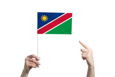 Güzel bir kadın eli, beyaz arka planda izole edilmiş diğer elinin parmağını gösterdiği bir Namibya bayrağını tutuyor..