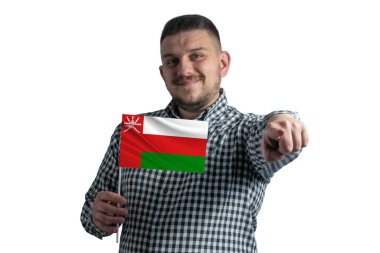 Umman 'ın bayrağını taşıyan beyaz bir adam beyaz bir arka planda yalnız başına önünü işaret ediyor..