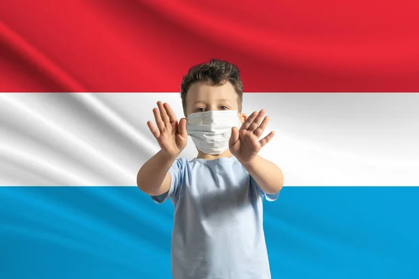 Mały Biały Chłopiec Masce Ochronnej Tle Flagi Luksemburga Robi Znak — Zdjęcie stockowe