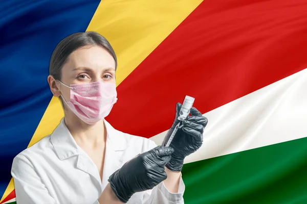 少女医師はセーシェルの旗を背景に予防接種を準備する 予防接種のコンセプトセイシェル — ストック写真