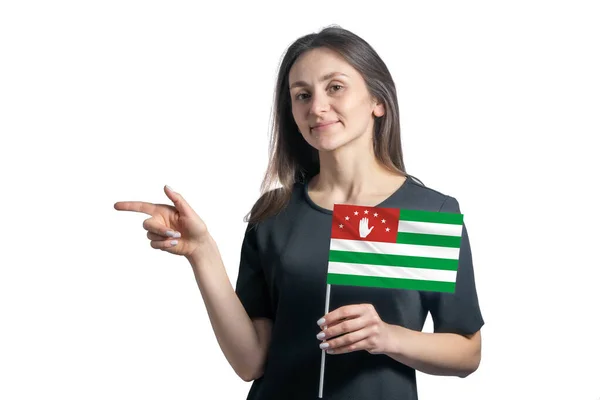 快乐的年轻白人妇女举着阿布哈兹国旗 指向左边 与白色背景隔离 — 图库照片