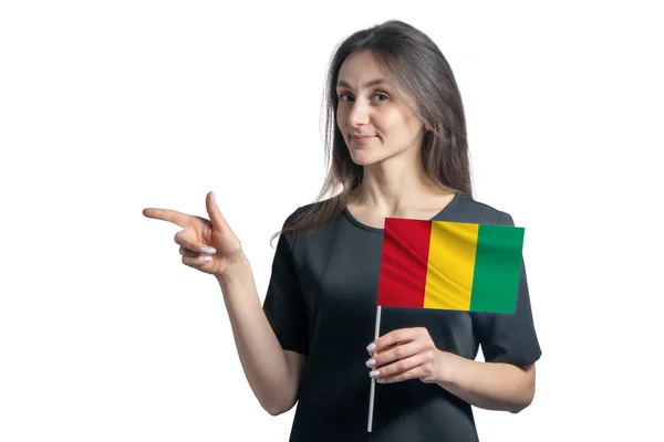 快乐的年轻白人女子举着几内亚国旗 指着左边的白色背景 — 图库照片