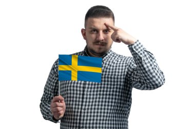 White guy holding a flag of Sweden and a finger touches the temple on the head isolated on a white background.