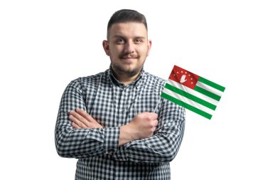 Beyaz adam elinde Abhazya bayrağı, beyaz bir arka planda kollarını kavuşturarak gülümsüyor..