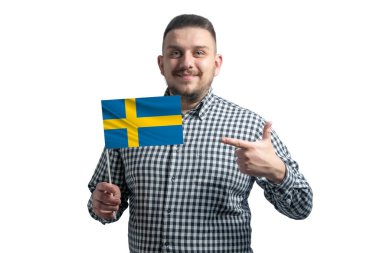 Beyaz adam İsveç bayrağını tutuyor ve diğer elini beyaz arka planda izole edilmiş bayrağa doğrultuyor..