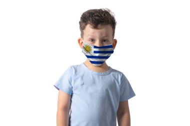 Uruguay bayrağı taşıyan bir solunum cihazı. Beyaz çocuk beyaz arka planda izole edilmiş tıbbi yüz maskesi takıyor..