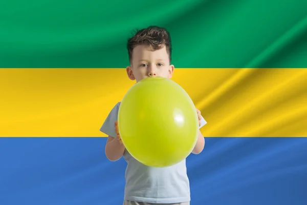 ガボンの子供の日 ガボンの旗を背景に風船を持った白い少年 こどもの日のお祝いのコンセプト — ストック写真