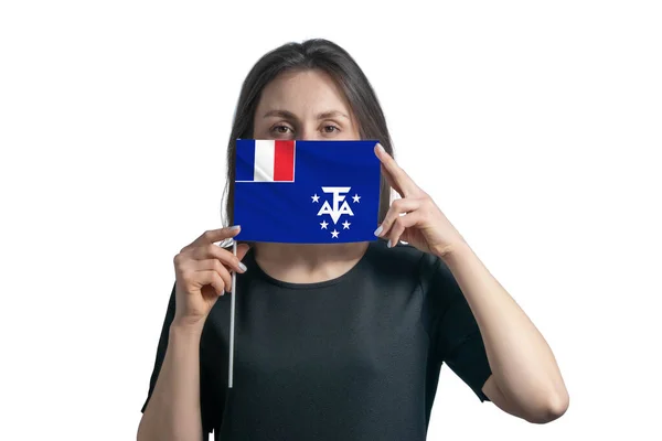 幸せな若い白人女性はフランス南部と南極地域の旗を持っており 白い背景にそれで彼女の顔をカバーしています — ストック写真
