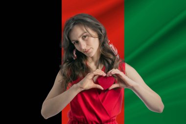 Afganistan 'ı seviyorum. Afganistan bayrağının arka planına karşı göğsünde bir kalp taşıyan bir kız. Vatanseverlik kavramı.