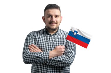 Elinde Slovenya bayrağı tutan beyaz bir adam beyaz bir arka planda kollarını kavuşturarak kendinden emin bir şekilde gülümsüyor..