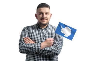 Beyaz adam Antarktika 'nın bayrağını tutuyor. Beyaz bir arka planda kollarını kavuşturup gülümsüyor..