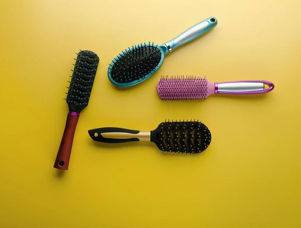 Various colored brushs and combs for hair on yellow background. Set of brush and hairbrush