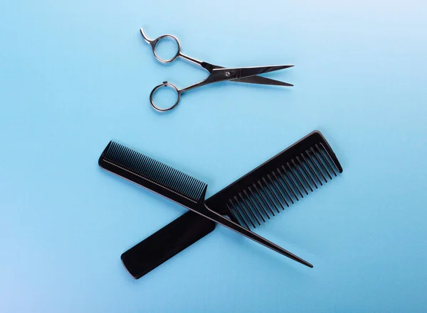 Hair combs and haircutting scissors on blue background professional isolated. Hairdresser equipment for hairstyle creating. Modern salon or barber concept