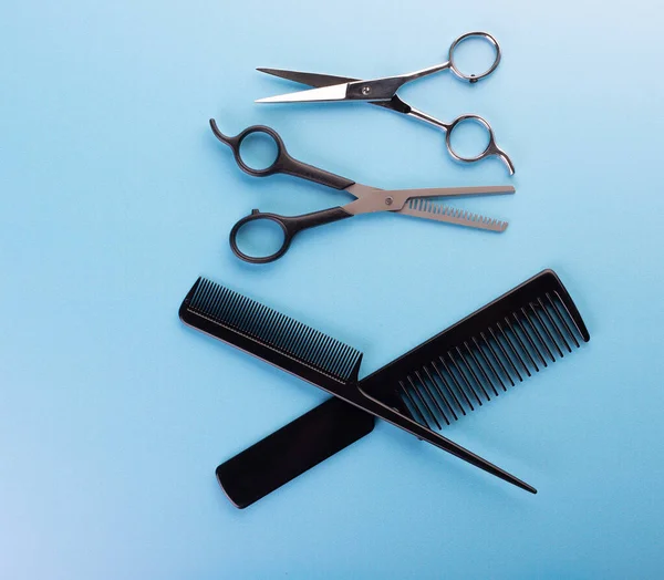 Professional tools for hairdresser isolated on blue background: hair combs and haircutting scissors. Hairdresser equipment for hairstyle in salon or barbershop concept
