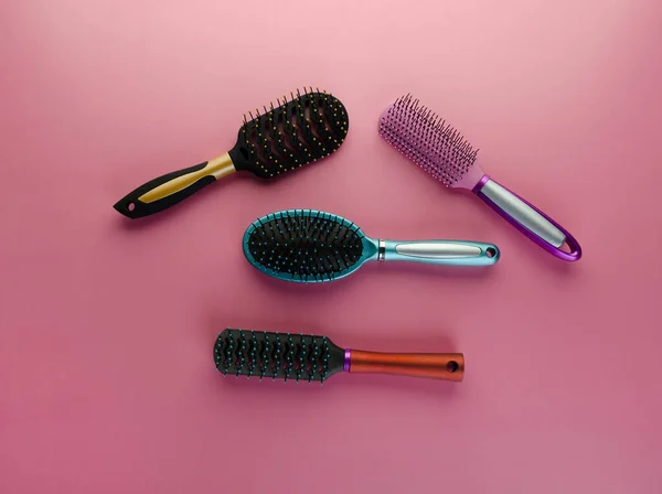 Various colored brushs and combs for hair on pink background. Set of brush and hairbrush
