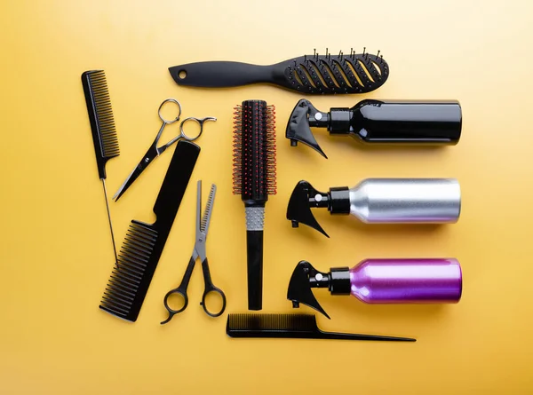 Hairdresser set with different tools on yellow background. Professional equipment for haircut isolated, top view. Hair combs, scissors and sprayers
