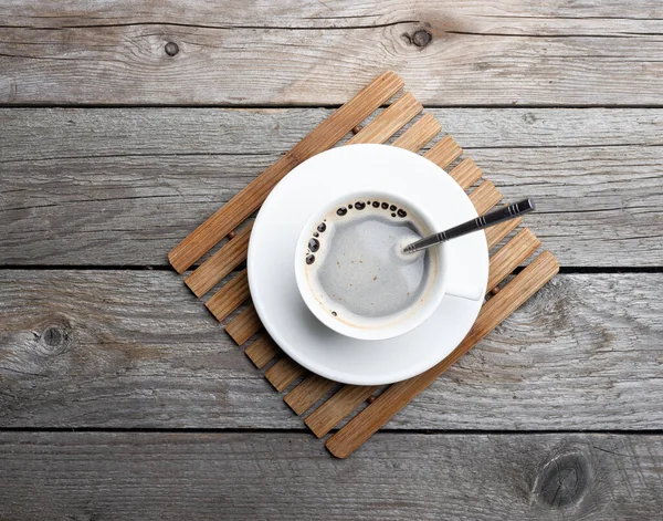 A cup of hot coffee on old wooden table in a cafe. White cup of coffee in the morning.