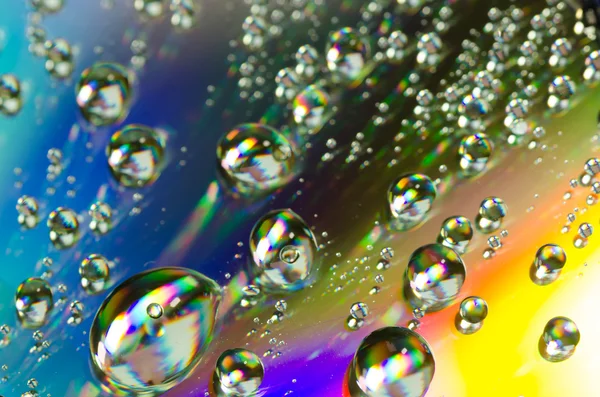 Gotas de agua sobre fondo de colores arco iris — Foto de Stock