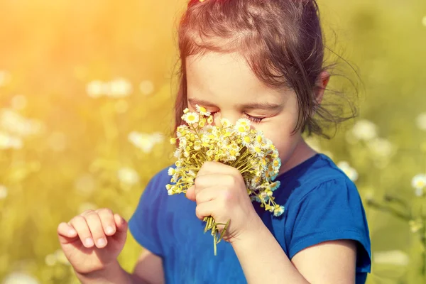 Kleines Mädchen schnuppert Blumen — Stockfoto