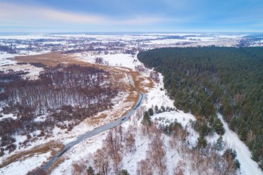 Kışın kırsal alan. Ormanın yukarısından ve çayırdaki derenin manzarası. Doğa arkaplanı