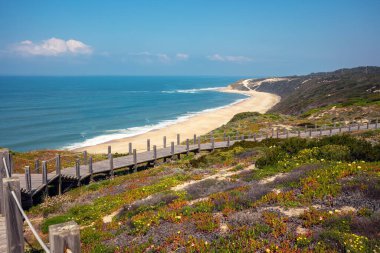 Paredes Panoramik Boardwalk. Güneşli bir günde, kayalık deniz kıyısındaki ahşap merdiven. Sahil Polvoeira, Portekiz
