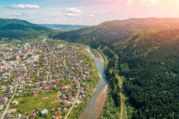 Aerial view of the mountains, mountain river and town in the valley in spring. Beautiful nature landscape. Carpathian mountains. Ukraine
