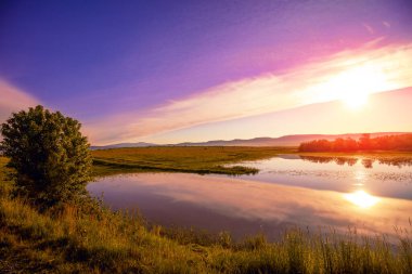 Gölün üzerinde büyülü bir günbatımı. Akşamları dingin göl. Doğa manzarası.