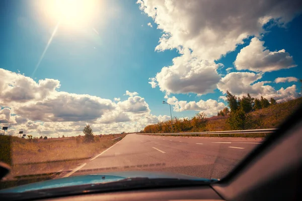 Driving a car on highway on a sunny day. Journey by car. View from car of road and beautiful cloudy sky. Ukraine, Europe