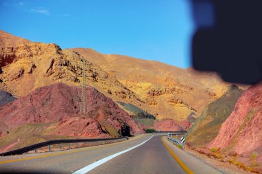 Dağ çölündeki otoyol. Yol boyunca kum taşı dağları. Arabadan görüntüle