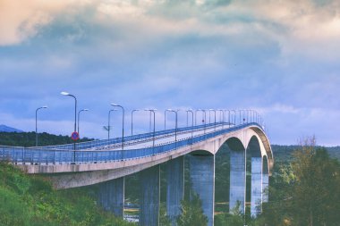 Gün batımında fiyort üzerinde kemer köprüsü. Saltstraumen, Norveç