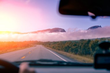 Gün batımında dağlara giden yol. Ön camdan görüntüyü al. Norveç 'in güzel doğası