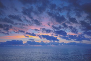 Denizin üzerinde gün batımı. Gün batımında renkli bulutlu bir gökyüzü. Rengi değişmiş. Gökyüzü dokusu. Soyut doğa arkaplanı