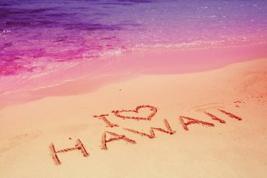 Plajda Hawaii 'ye bayılırım. Hawaii gün batımında kumsalda yazılmış.