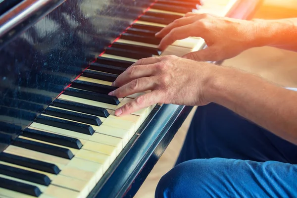 A man plays an old piano. Male hands on the keys of a vintage grand piano