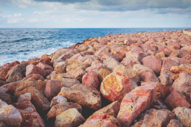 Kırmızı ve turuncu taşlı Rocky plajı. Harry S. Truman Caddesi kıyısında, Tel Aviv-Jaffa, İsrail