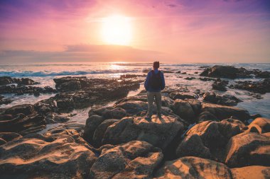 Akşamları deniz manzarası. Gün batımında Rocky sahili. Sahilde sihirli bir gün batımına bakan turist silueti. Porto, Portekiz
