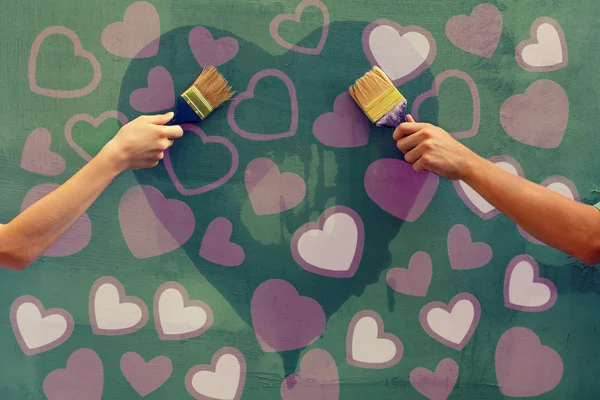 Male and female hands painting hearts — Stock Photo, Image