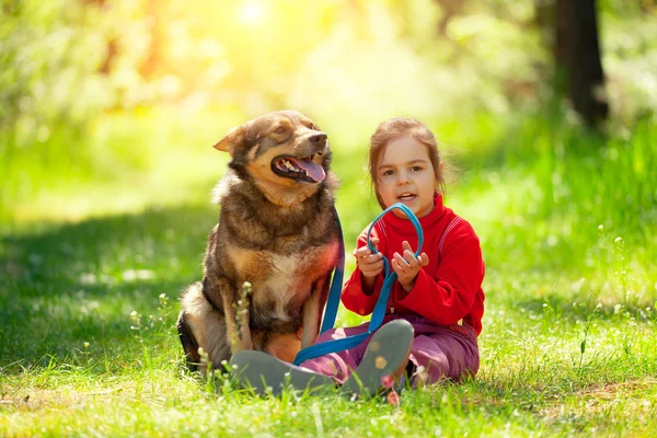 Flicka med hund i sommarträdgård — Stockfoto