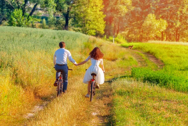 Bride and groom riding bicycles — Stock Photo, Image